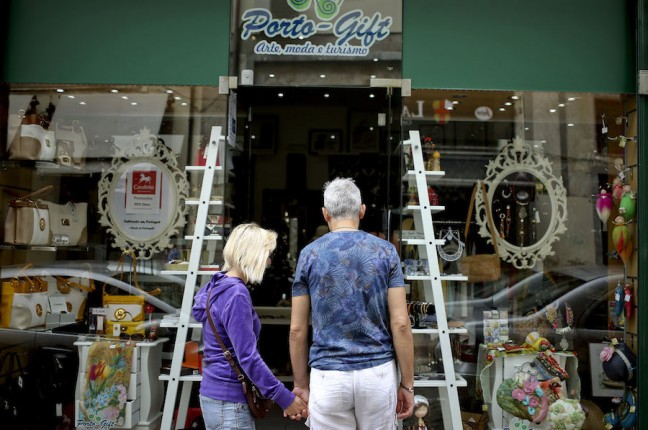 Um casal de turistas observa a montra da Porto Gift, uma das muitas lojas de lembranças que surgiram no Porto com o aumento de visitantes